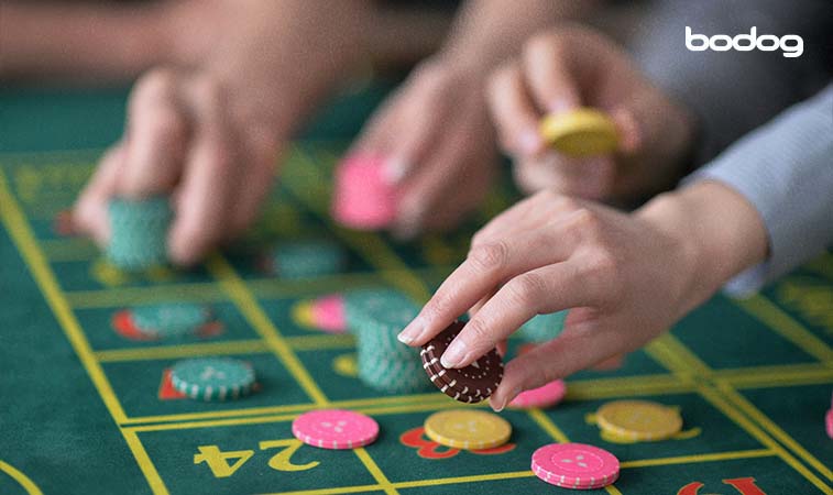 primer plano de las manos de una persona colocando fichas en una mesa de ruleta