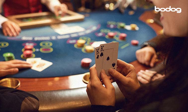 persona mostrando dos cartas frente a una mesa de casino