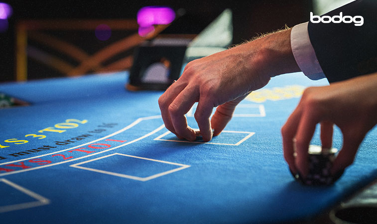 Jogadores segurando fichas em uma mesa de Baccarat