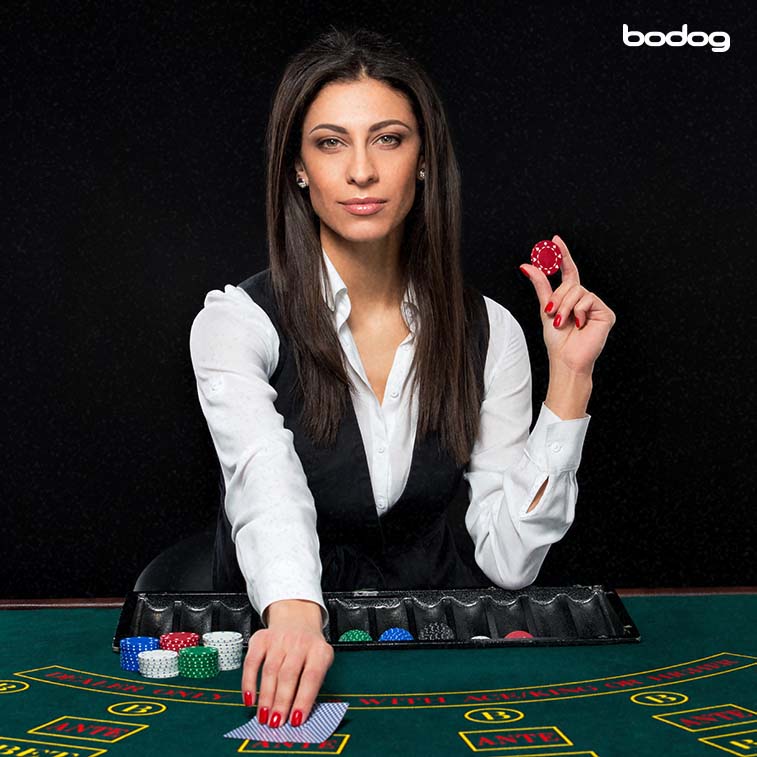 Dealer de casino levantando carta y sosteniendo una ficha