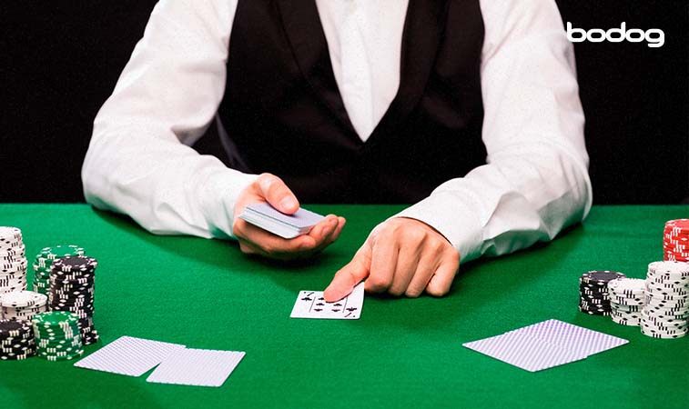 distribuicao cartas dealer Dealer colocando uma carta na mesa de poker. Fichas de poker estão ao lado