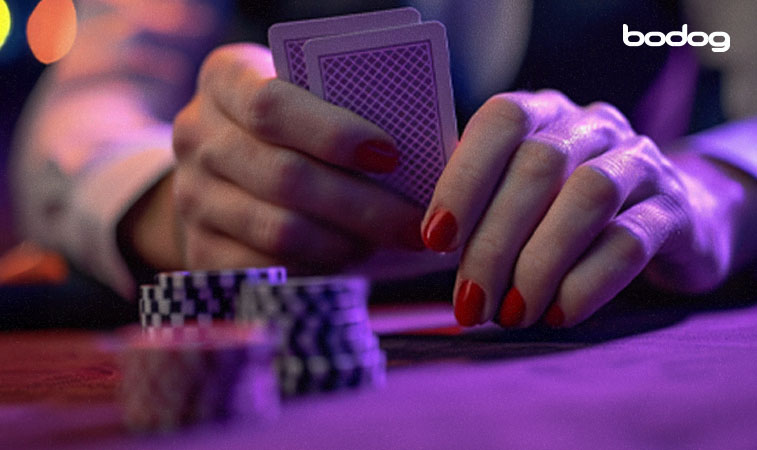 mãos femininas seguram duas cartas ocultas, perto de fichas