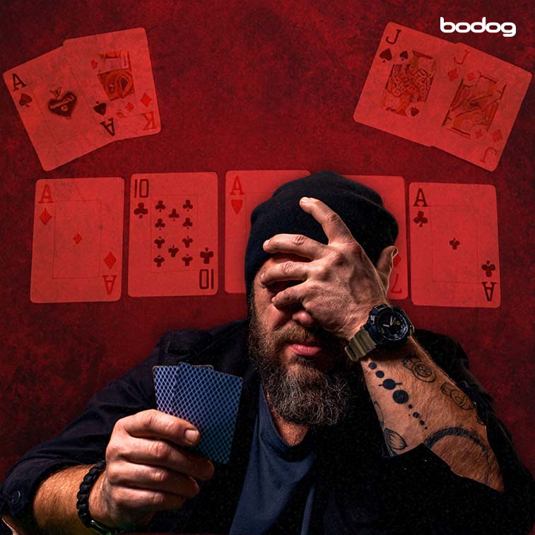 hombre con dos cartas en una mano y tapándose la cara con la otra mano