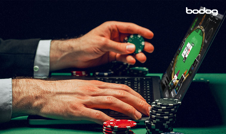 homem segurando uma ficha de poker com um computador aberto em um torneio de poker