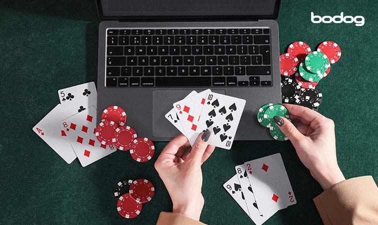 Mulher com fichas e baralhos na mão em frente ao notebook