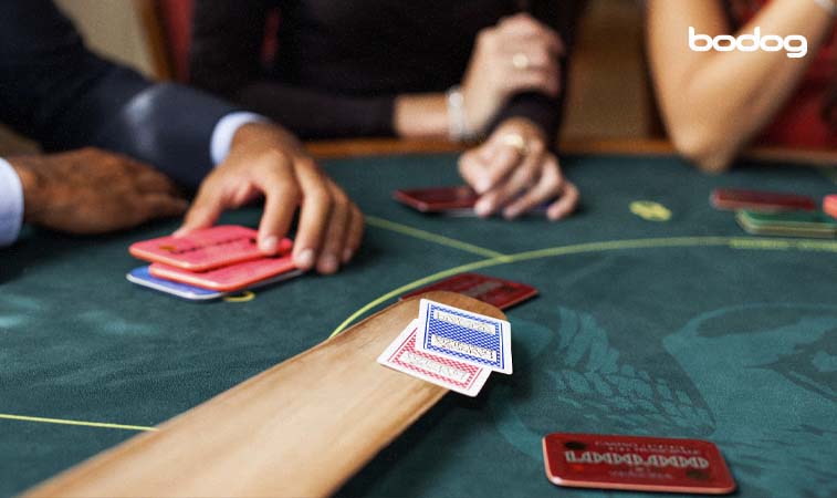 jugadores sentados al rededor de una mesa jugando al baccarat