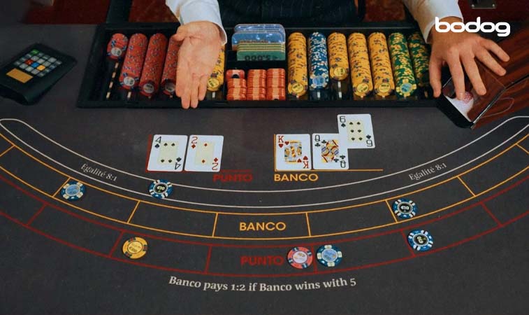 Crupier luego de repartir cartas al punto y a la banca en mesa de Punto y Banca