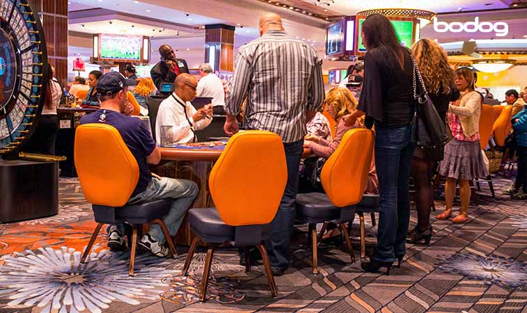 pessoas sentadas e em pé ao redor de uma mesa de poker