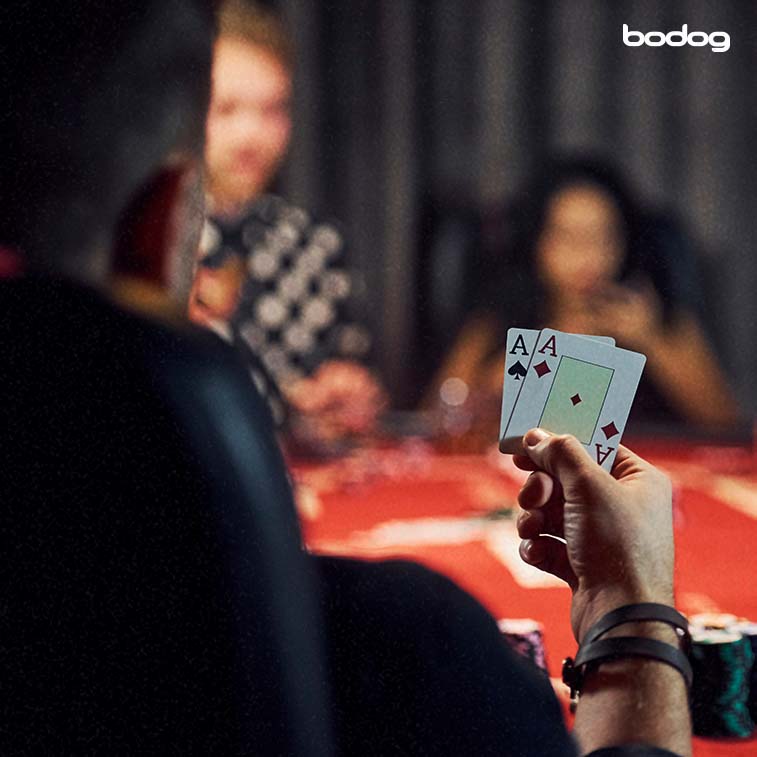 pessoa jogando poker segurando dois Ases