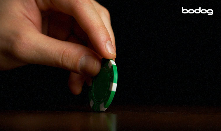 mão segurando ficha de poker