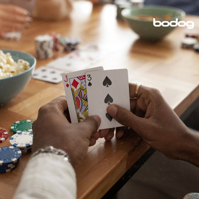 Pessoa segurando as cartas do baralho J e 3 em jogo com amigos