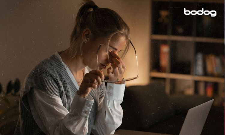 Mujer cansada frente su computadora y la luz apagada