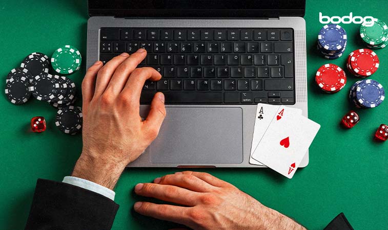 Manos en computadora con cartas y fichas de poker