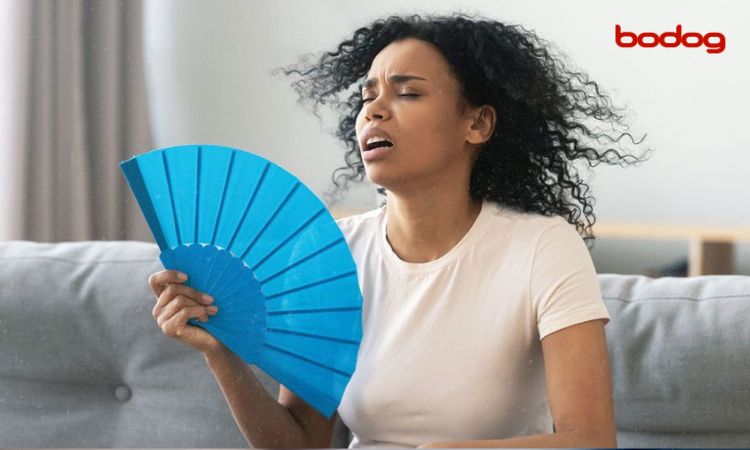 Mujer con calor, abanicándose con un abanico azul.