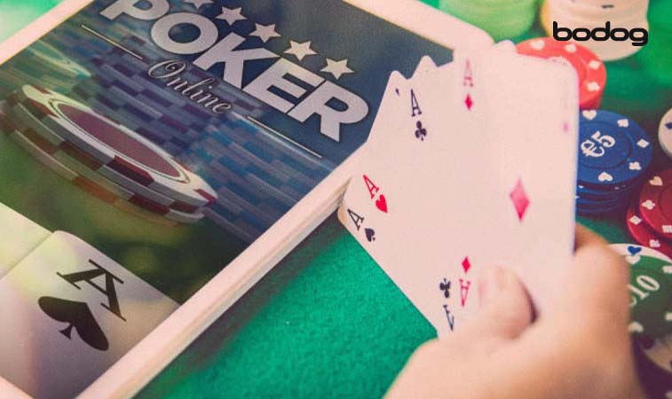 Mano con cartas de poker al lado de tablet